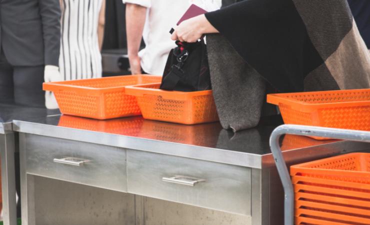 People in line at the bag check with orange trays