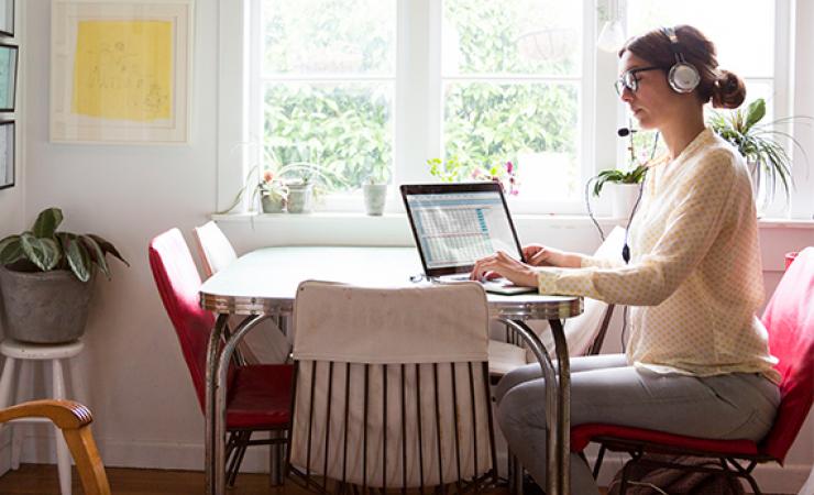 Woman with headphones working by window in Dining room