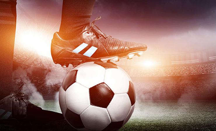 Footballer resting boot on top of a football/soccer ball