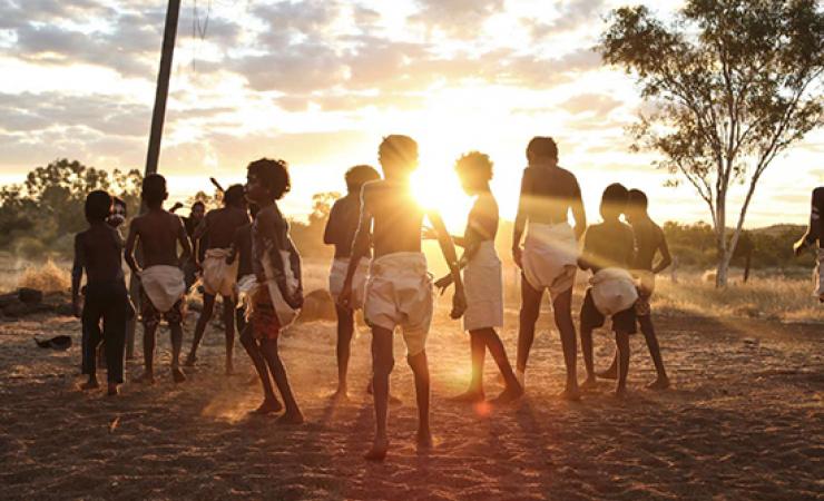 Children looking out over a field at the sunset