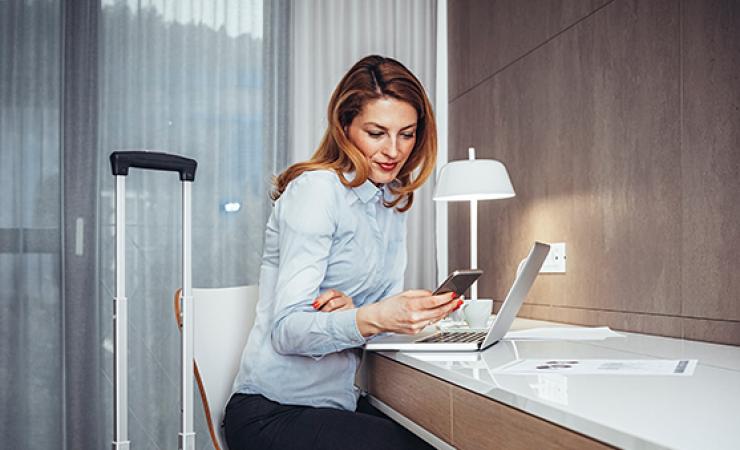 Woman at desk in hotel room on phone.