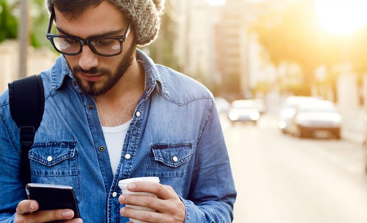 Man walking in street looking at phone 