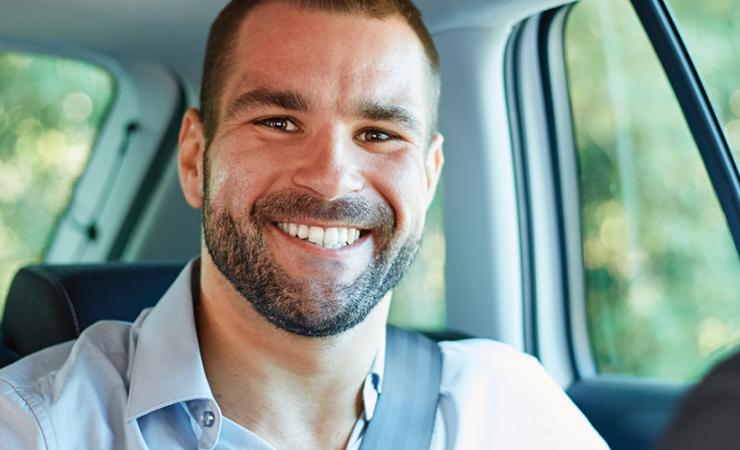 Man smiling in backseat of car