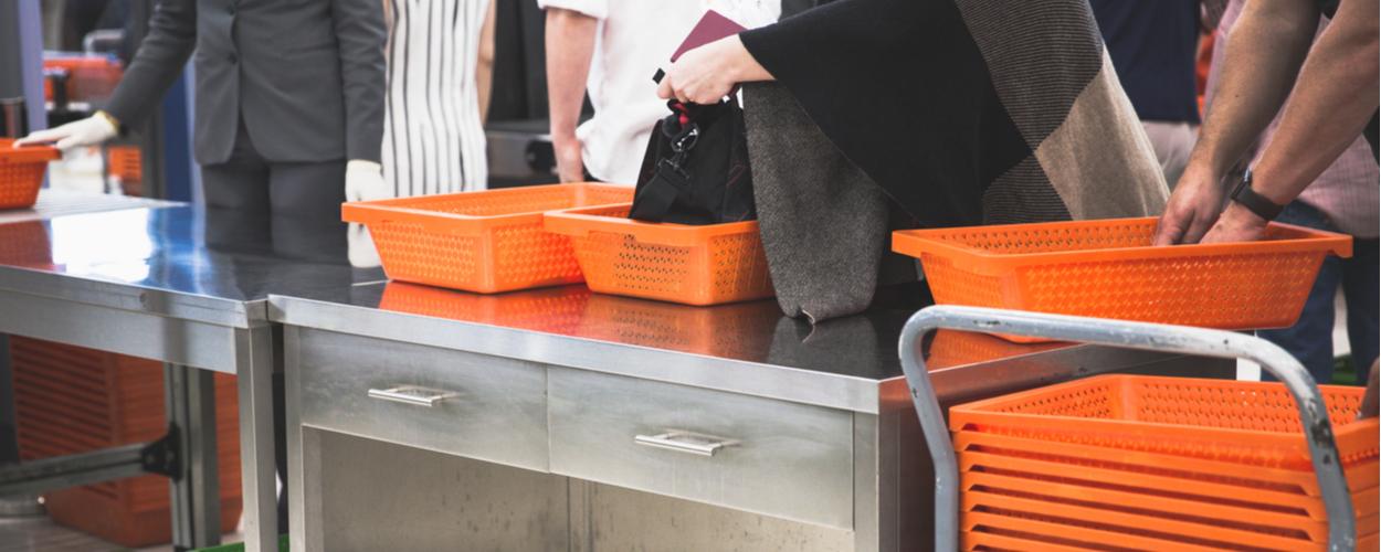 People in line at the bag check with orange trays