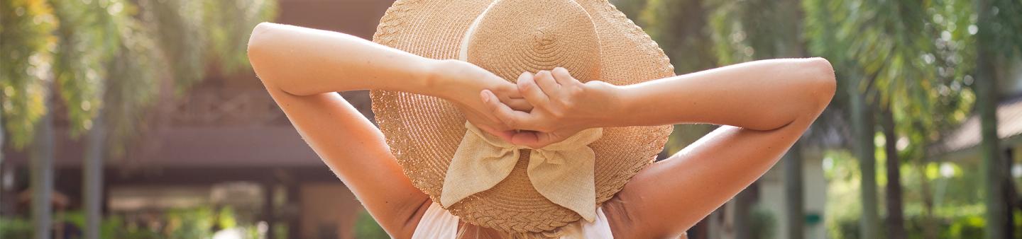 Lady with large hat sitting relaxing by the pool