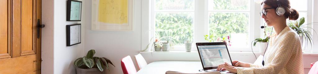 Woman with headphones working by window in Dining room