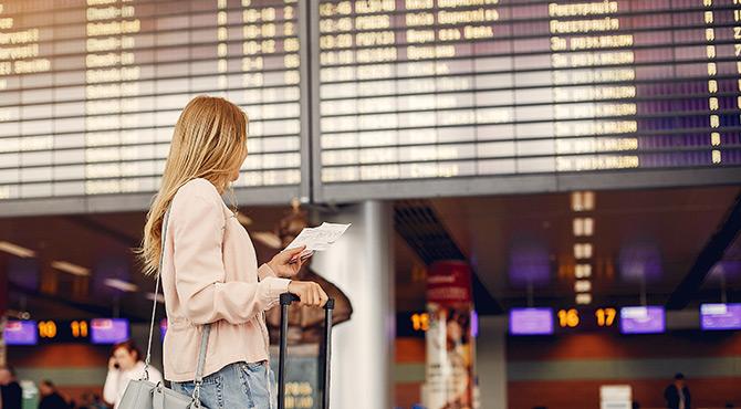 Woman standing at airport departure board