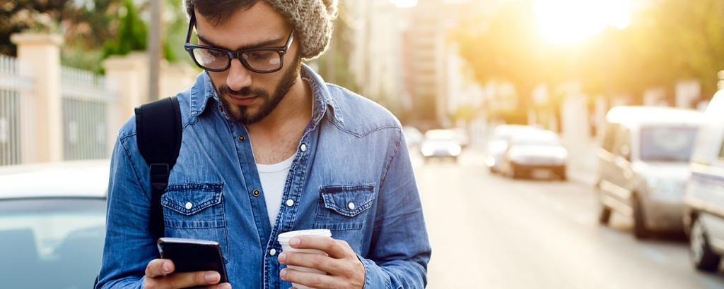 Man walking in street looking at phone 