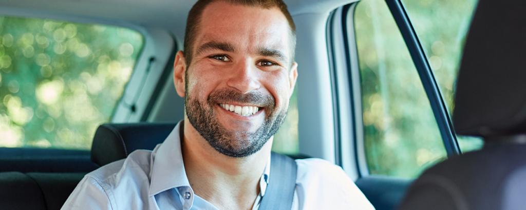 Man smiling in backseat of car